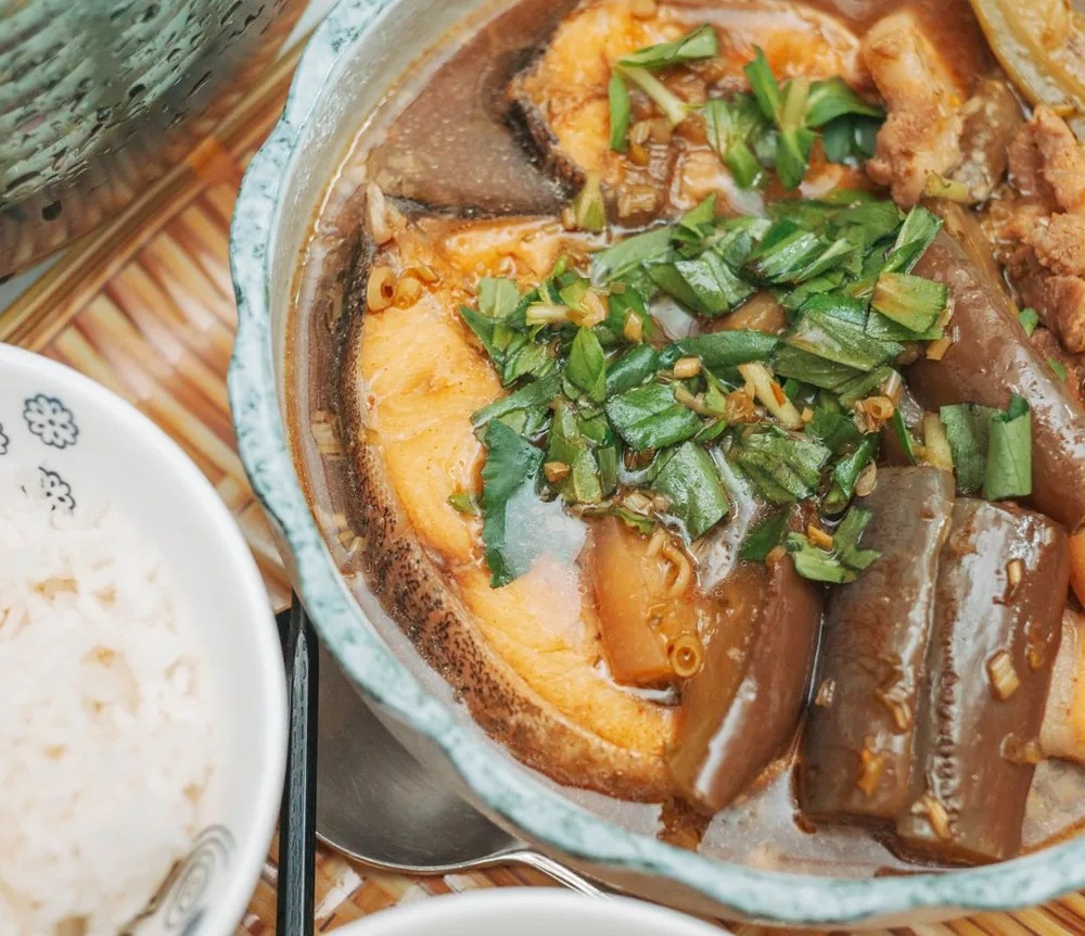 Nồi cá kho với hành lá và bát cơm trắng