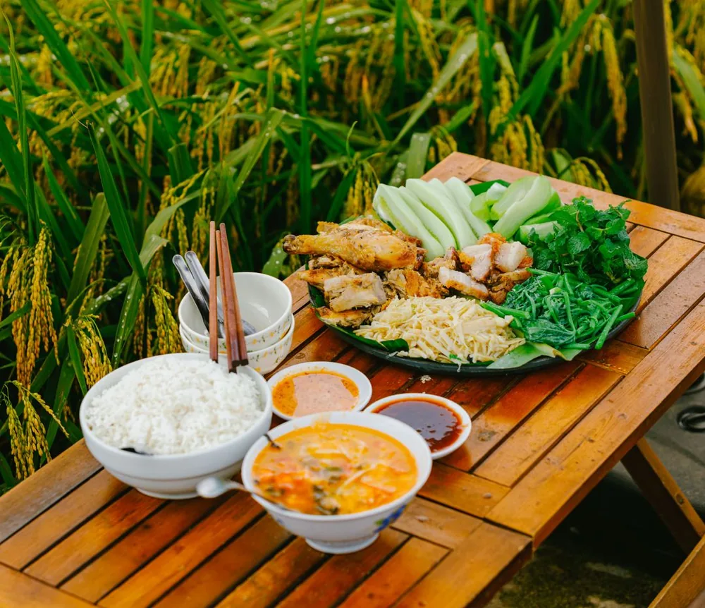 Bàn cơm gỗ bày cạnh ruộng lúa chín