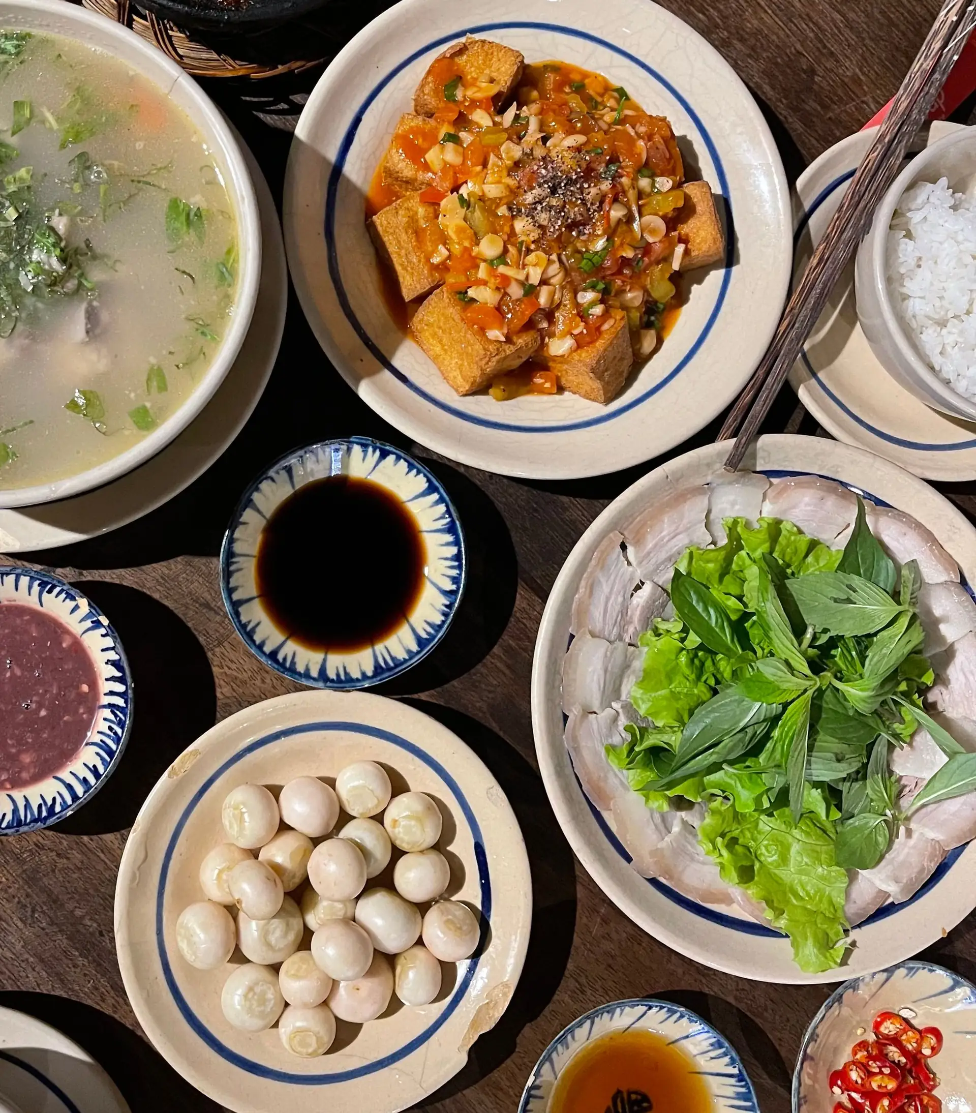 Mâm cơm gia đình Việt với canh, đậu sốt cà, cá kho tộ và thịt luộc cuốn rau