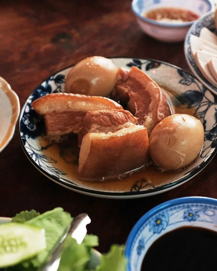 Thịt kho trứng bên đĩa dưa món và chén nước tương