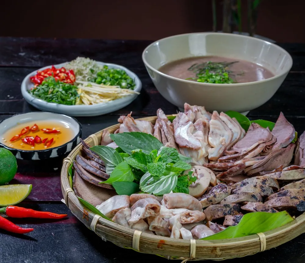 Thịt luộc bày trong rổ tre với rau thơm, ớt và nước chấm